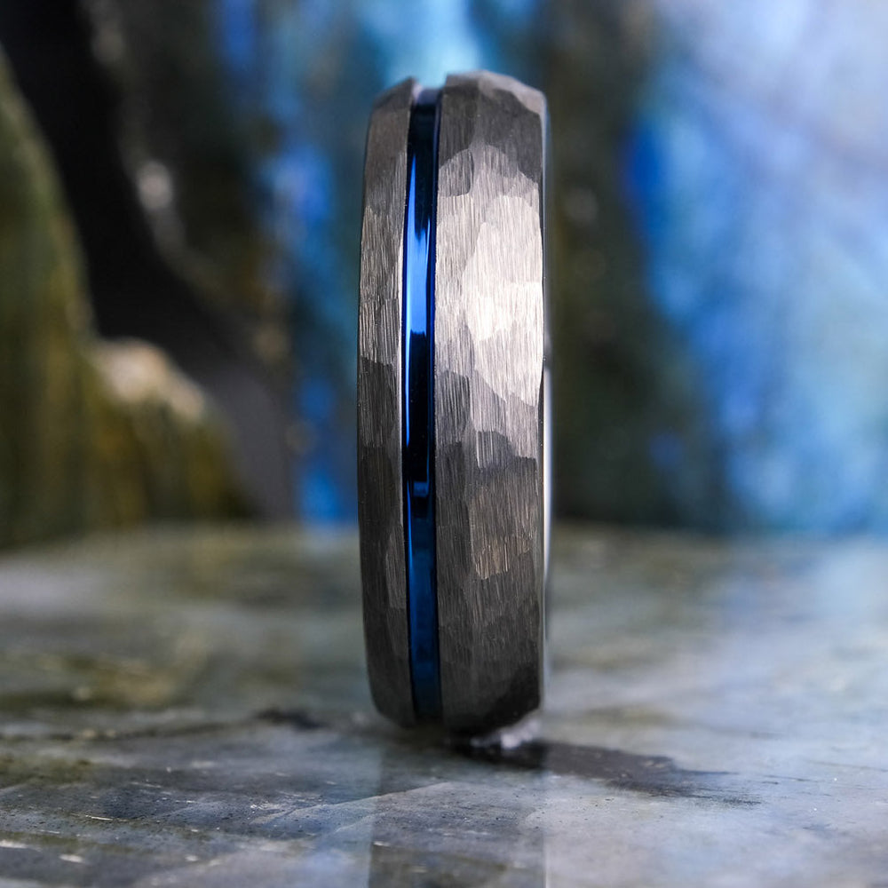 Silver ring with a blue stripe on a stone surface with a blurred natural background