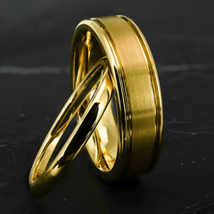 His and hers polished yellow gold wedding bands on a black stone surface.