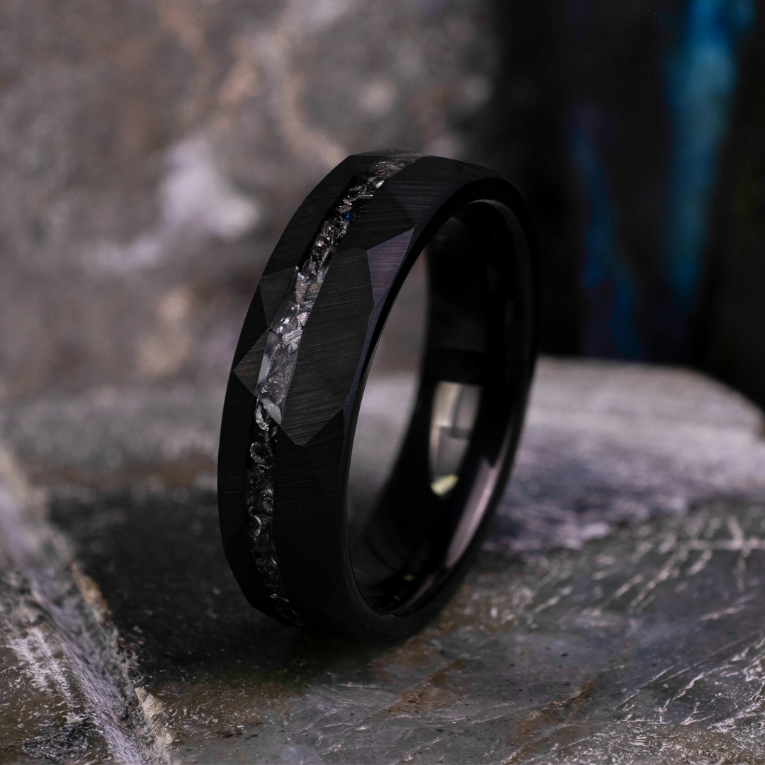 6mm black hammered tungsten carbide wedding band with a crushed meteorite stripe,  on top a large grey stone. 