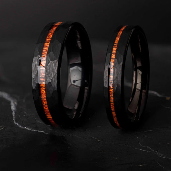 Black hammered koa wood stripe his and hers 6mm ad 4mm band on a black stone.