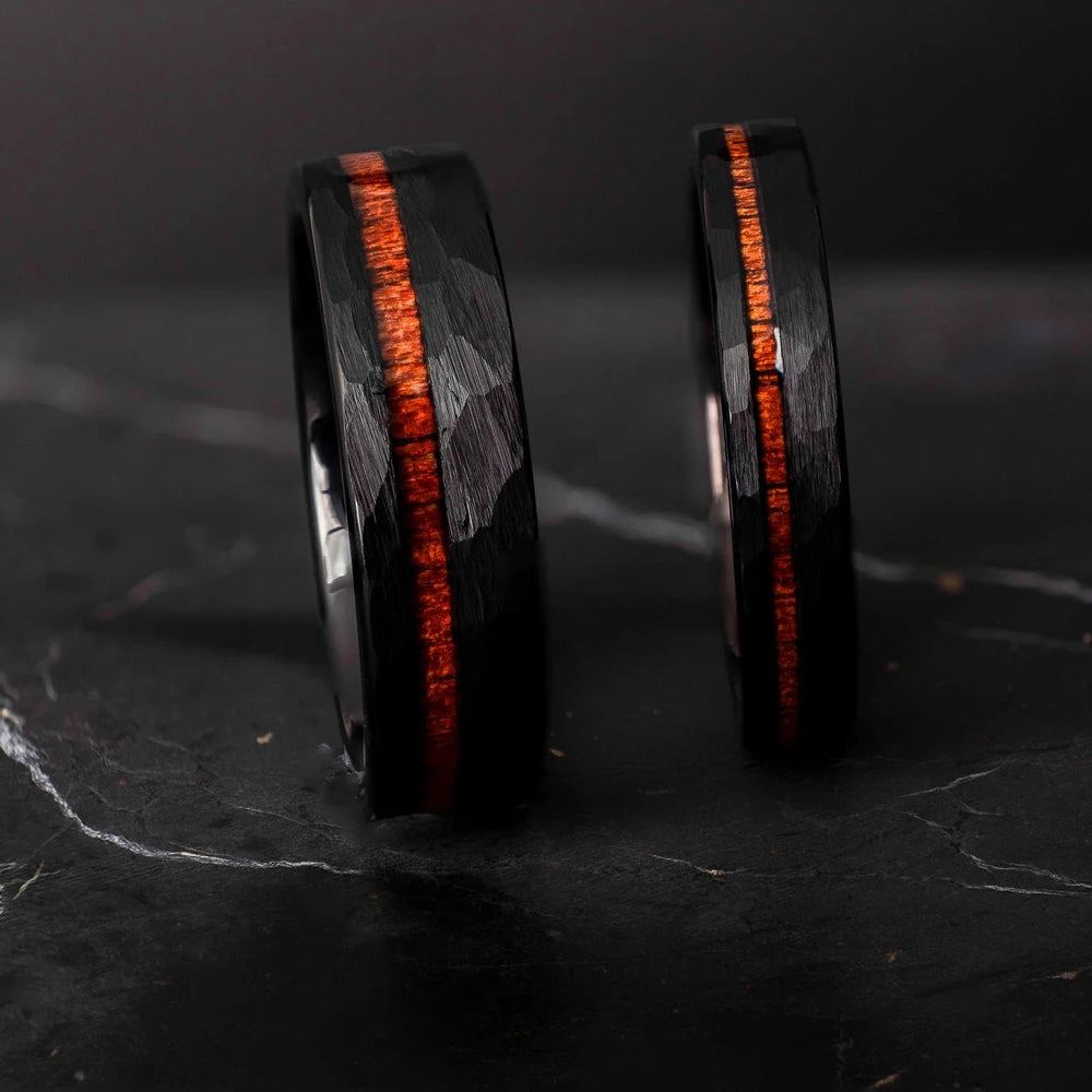 Black hammered koa wood stripe his and hers 6mm ad 4mm band on a black stone.