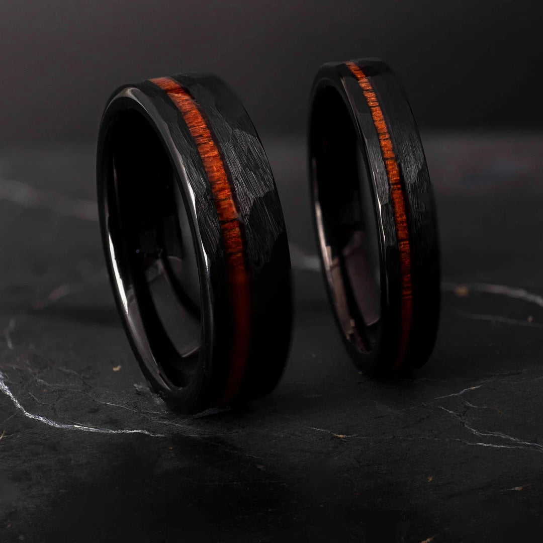 Black hammered koa wood stripe his and hers 6mm ad 4mm band on a black stone.