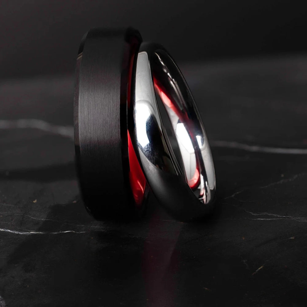 Black and silver tungsten carbide ring on a dark marble surface
