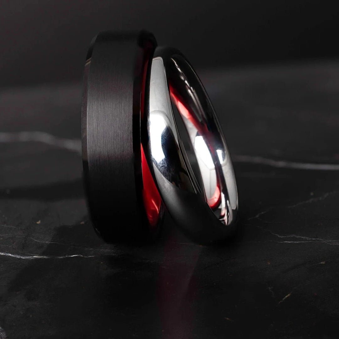 Black and silver tungsten carbide ring on a dark marble surface