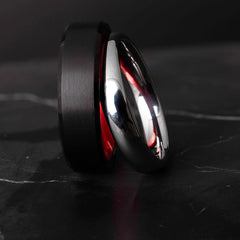 Black and silver tungsten carbide ring on a dark marble surface