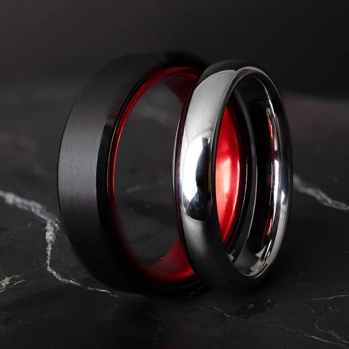 Black and silver tungsten carbide ring on a dark marble surface