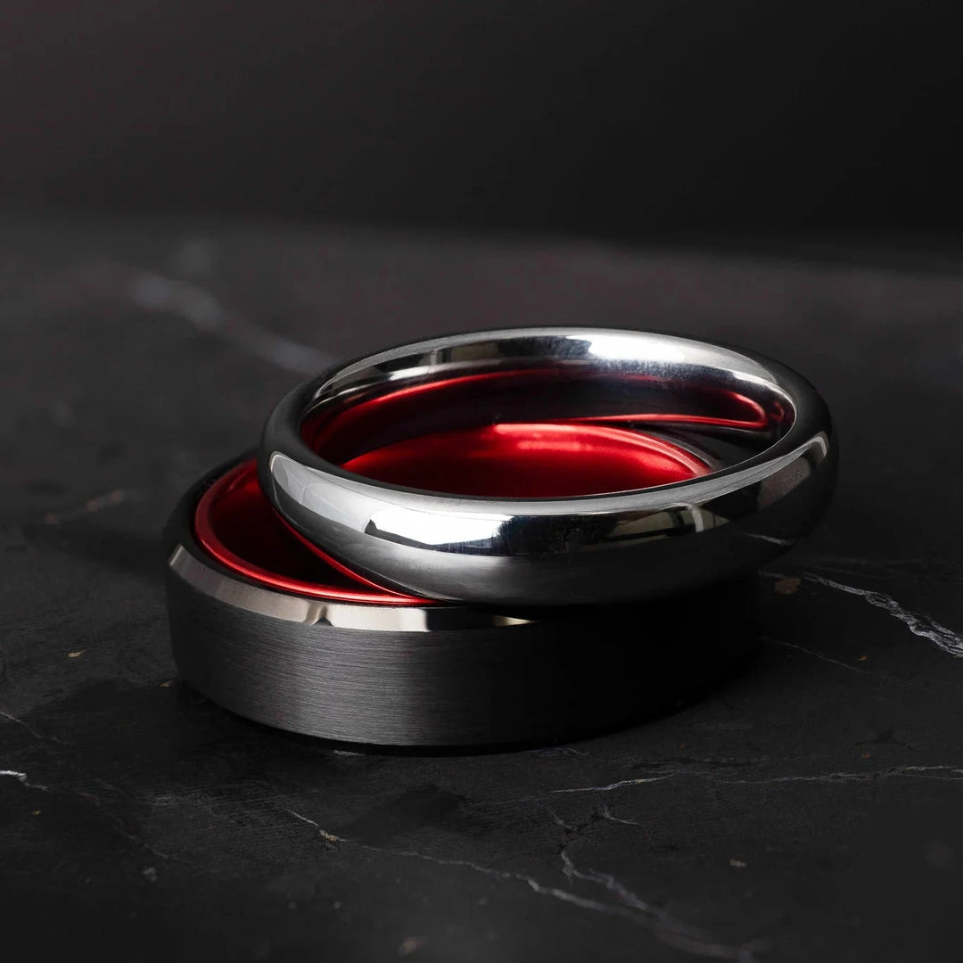 Black and silver tungsten carbide ring on a dark marble surface