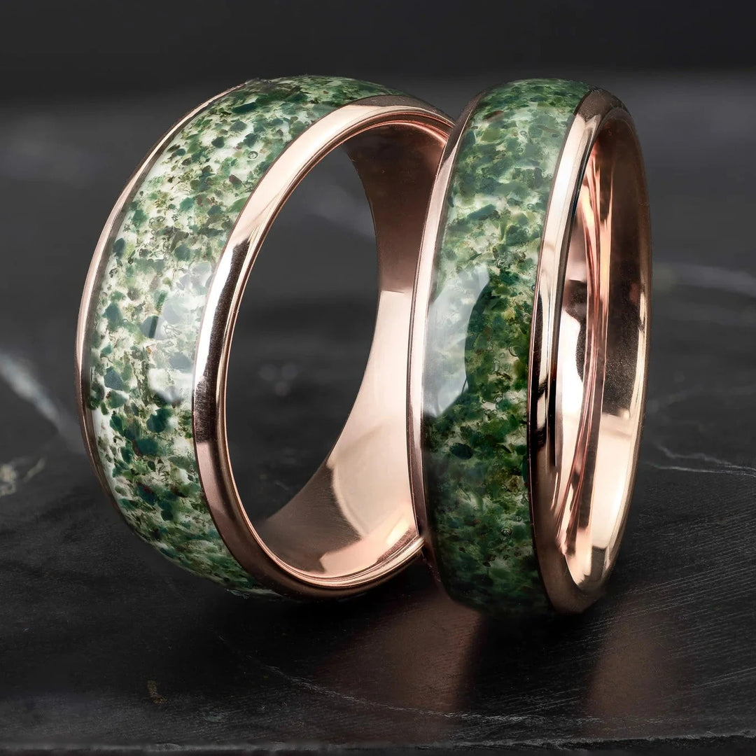 His and hers moss agate tungsten carbide wedding bands in 6mm and 8mm on a black marble stone.