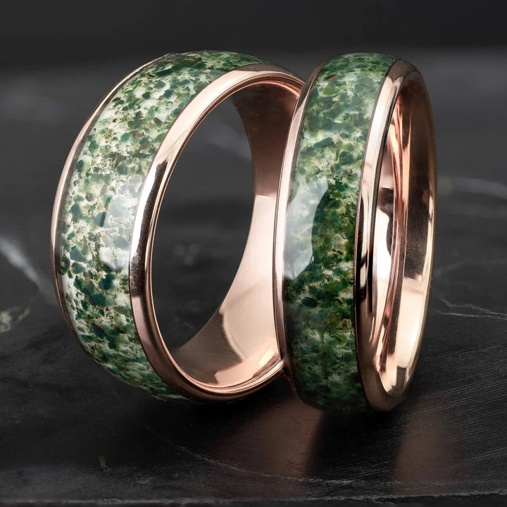 His and hers moss agate tungsten carbide wedding bands in 6mm and 8mm on a black marble stone.