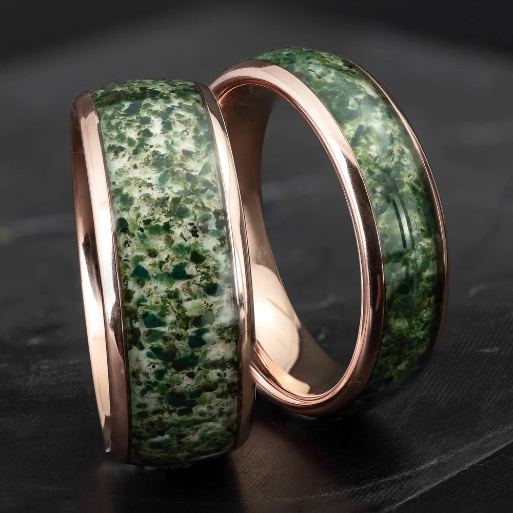 His and hers moss agate tungsten carbide wedding bands in 6mm and 8mm on a black marble stone.