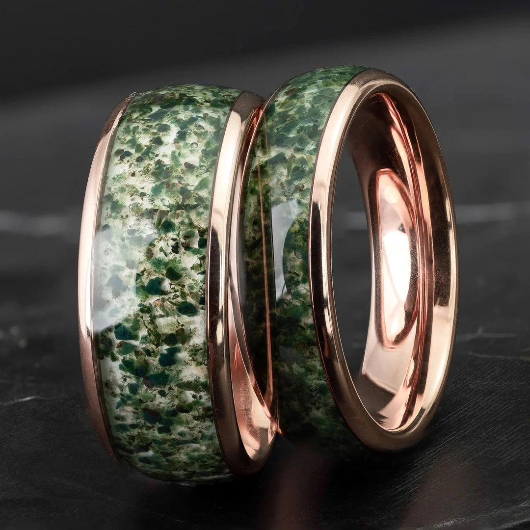 His and hers moss agate tungsten carbide wedding bands in 6mm and 8mm on a black marble stone.