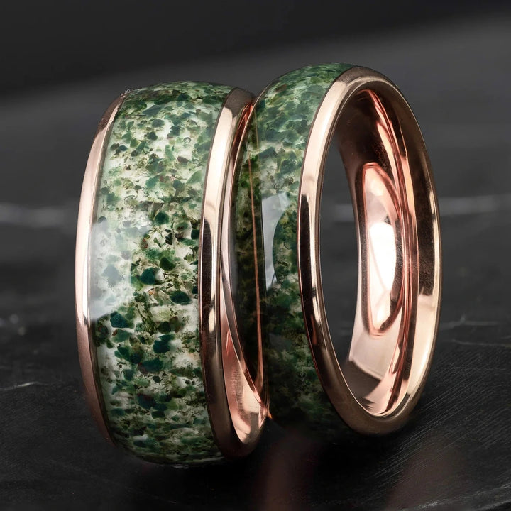 His and hers moss agate tungsten carbide wedding bands in 6mm and 8mm on a black marble stone.
