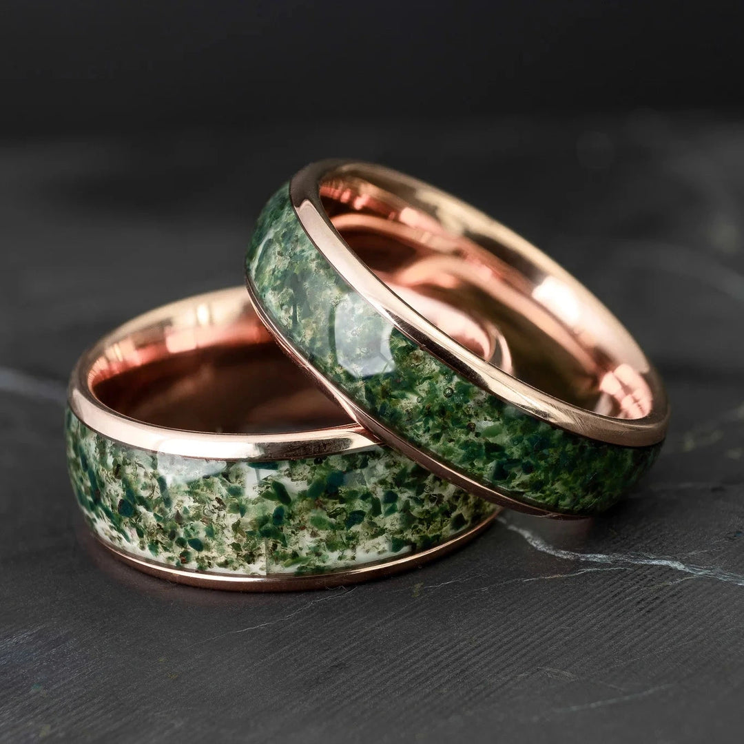 His and hers moss agate tungsten carbide wedding bands in 6mm and 8mm on a black marble stone.