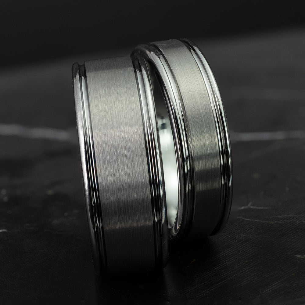 His and hers silver polished edge set 6mm and 8mm tungsten carbide bands on a black marble stone.